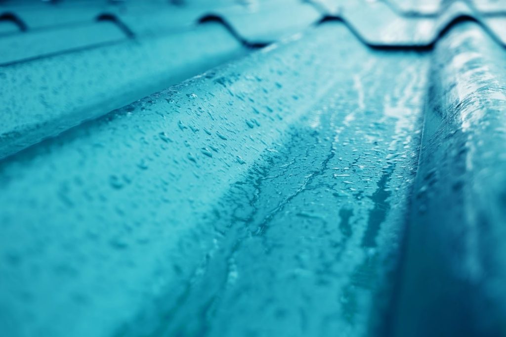 Rainwater running over blue metal roof tiles — spring roof inspection, Roanoke